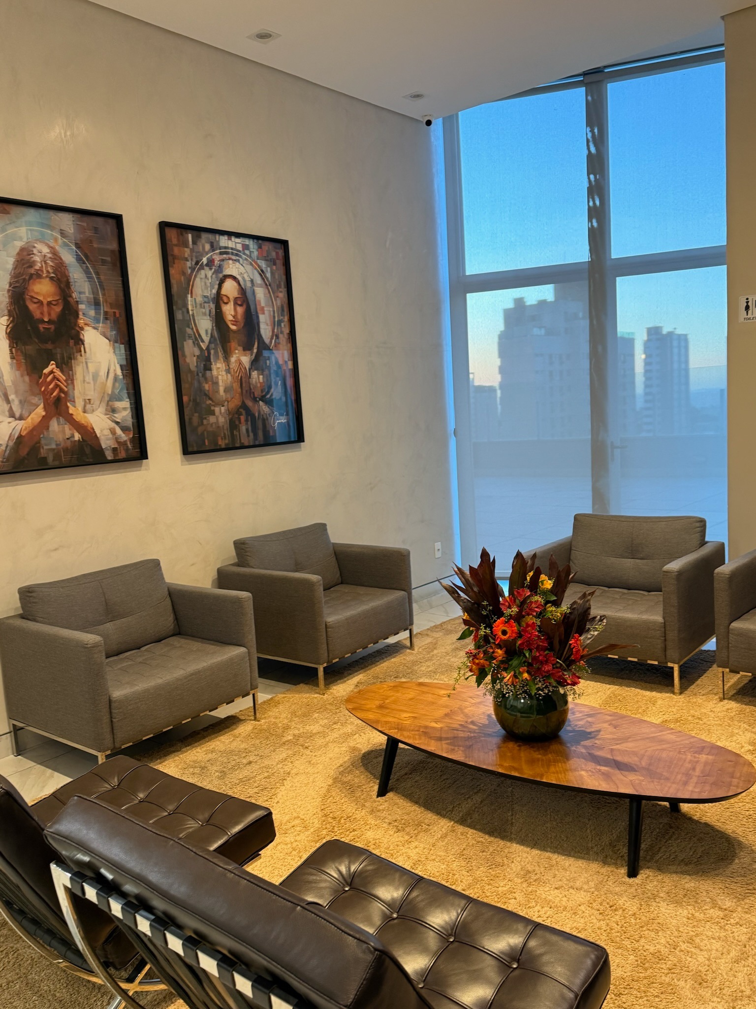 Recepção da AngioGold no Belvedere — poltronas, mesa de centro com arranjo floral e vista panorâmica de Belo Horizonte