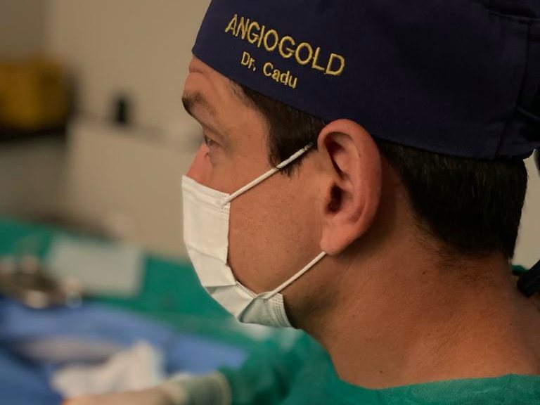 Dr. Cadu paramentado, com touca da AngioGold, durante procedimento