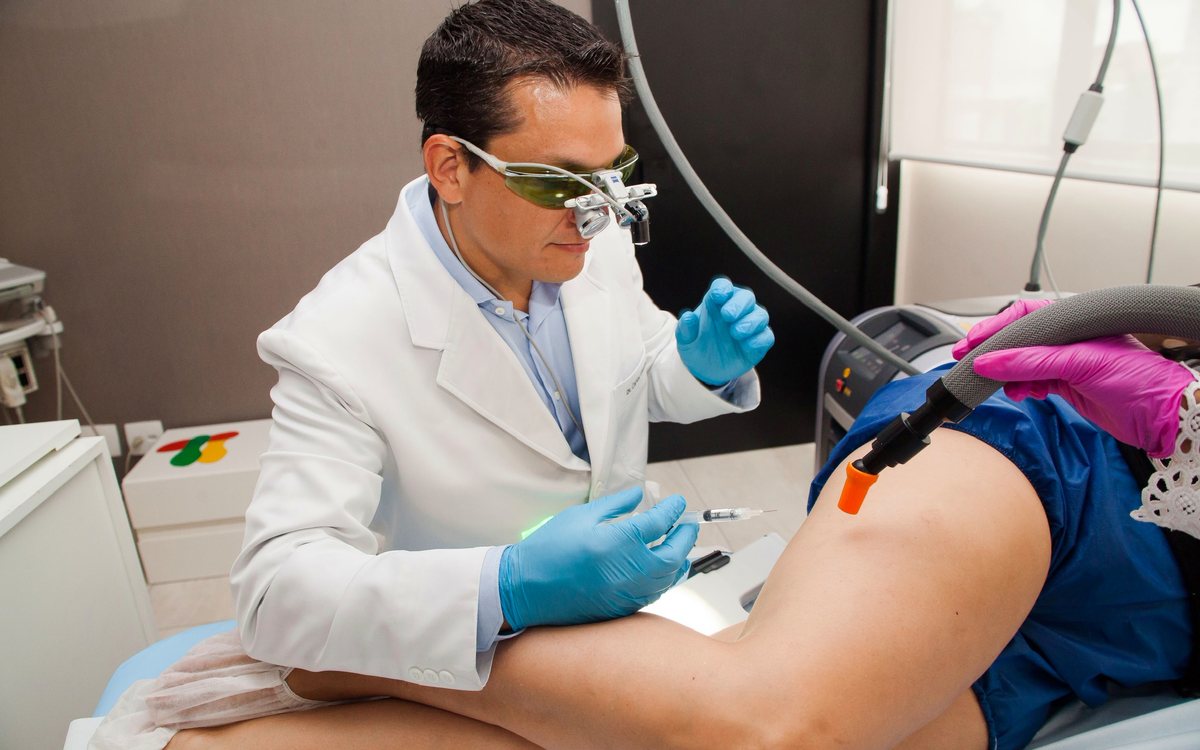 Dr. Cadu aplicando escleroterapia com lupa de aumento e óculos de proteção