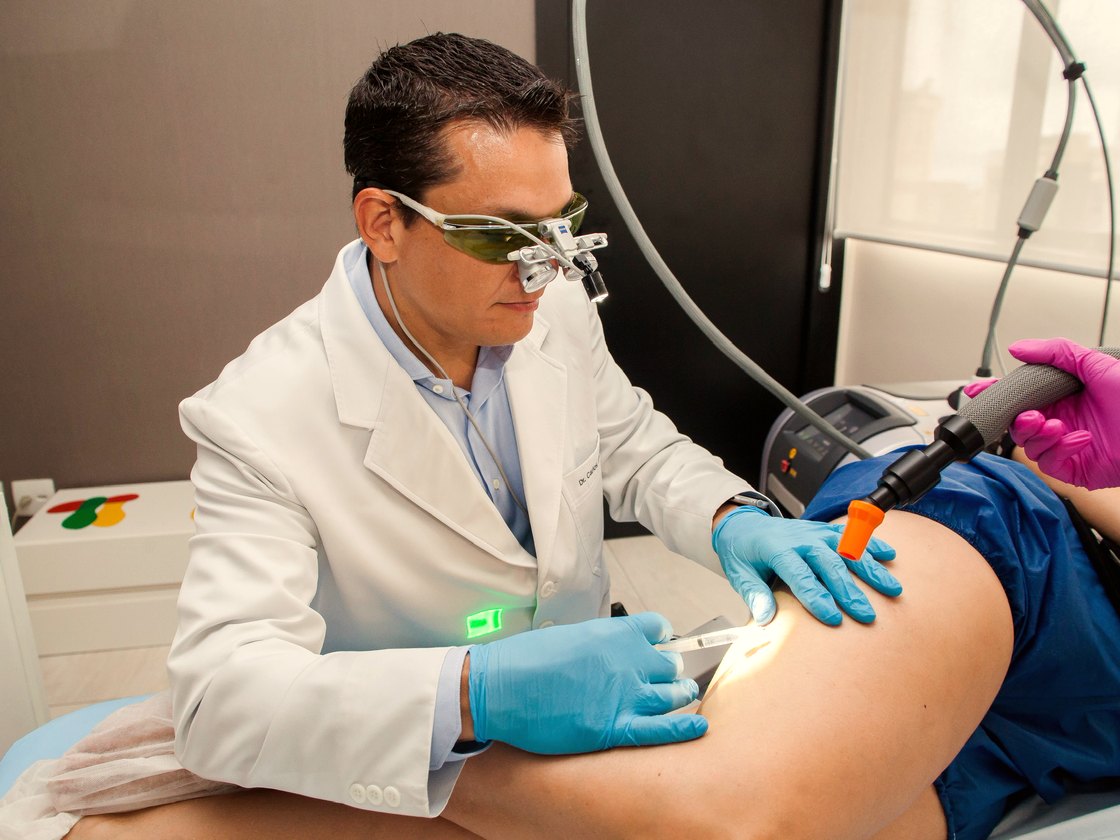 Dr. Cadu aplicando o laser transdérmico por fora da pele da perna