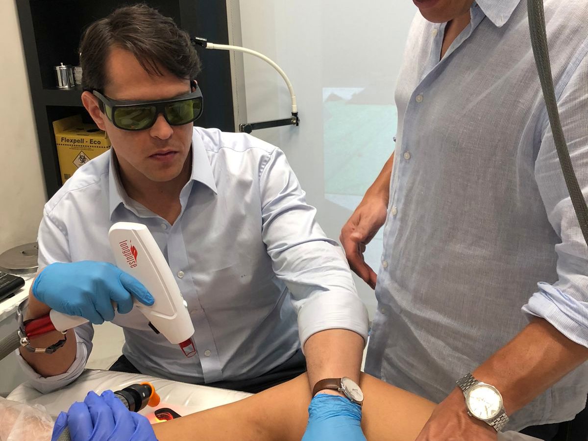 Aplicação de laser com ponteira de pulso longo na perna da paciente